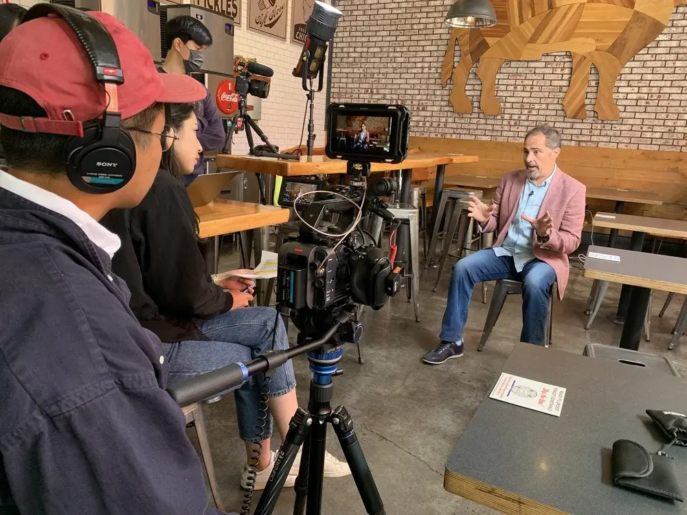 Camera and sound crew filming an interview inside a restaurant